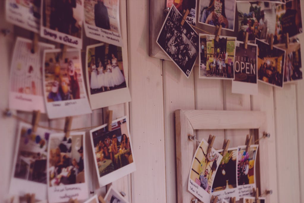 Collection of vintage Polaroid photos clipped to a wooden wall indoors.